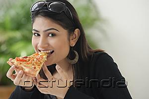 PictureIndia - Woman eating a slice of pizza