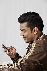 PictureIndia - side profile of young man in jacket, using mobile phone
