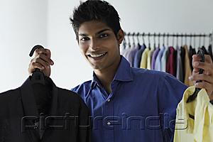 PictureIndia - young man holding up two shirts and smiling