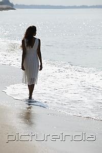 PictureIndia - back view of woman wearing white dress and walking along the beach