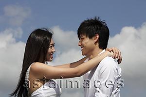 Asia Images Group - young couple looking at each other and smiling with blue sky as background