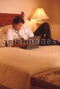 Asia Images Group - Male executive in hotel room using laptop computer