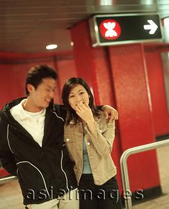 Asia Images Group - Young man and woman talking in train station.
