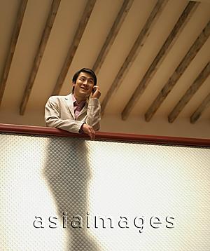 Asia Images Group - Young man on mobile phone, low angle view
