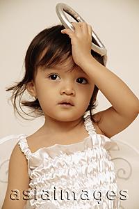 Asia Images Group - Young girl looking away, holding up her costume halo.