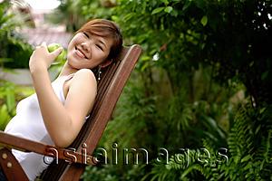 Asia Images Group - Young woman sitting on chair, outdoors.