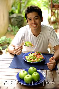 Asia Images Group - Man eating salad, looking at camera