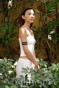 Asia Images Group - Young woman standing, looking away, portrait