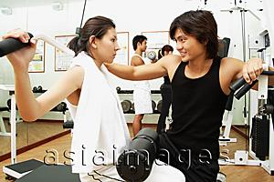 Asia Images Group - Couple working out in gym, weight training, people in the background