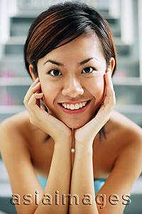 Asia Images Group - Young woman, smiling at camera, hands on face