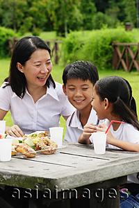 Asia Images Group - Mother with two children, sitting at picnic table