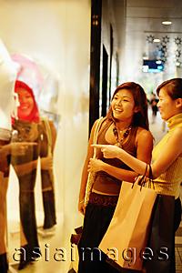 Asia Images Group - Young women window shopping, standing outside window display