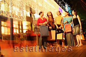 Asia Images Group - Young women standing side by side, in a row, carrying shopping bags