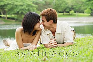 Asia Images Group - Couple lying on grass, face to face