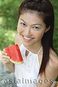 Asia Images Group - Woman holding slice of watermelon, smiling at camera