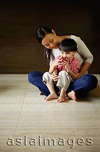 Asia Images Group - Mother with young son sitting on floor, boy drinking