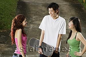 Asia Images Group - Three teenagers talking, young man holding skateboard