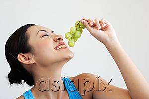 AsiaPix - Woman holding grapes near mouth, side view