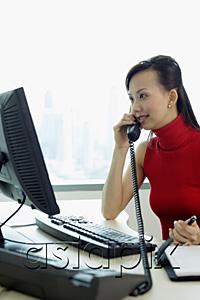 AsiaPix - Female executive sitting at office desk, using telephone
