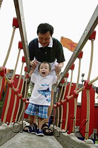 AsiaPix - Father with young son in playground, walking on bridge