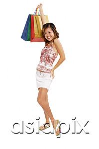AsiaPix - Young woman standing with hand on hip, carrying shopping bags