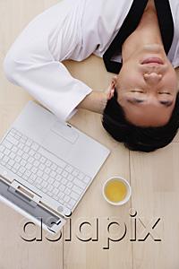 AsiaPix - Man lying on floor, hands behind head, laptop next to him