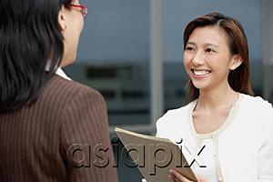 AsiaPix - Female executive handing folders over to woman in front of her