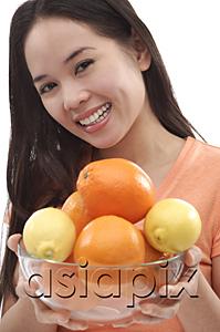 AsiaPix - Young woman holding bowl of oranges and lemons