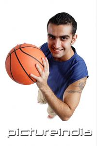 PictureIndia - Young man holding  basketball, looking at camera