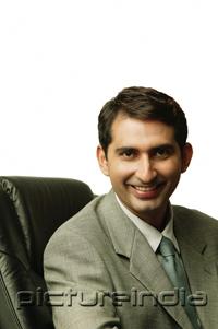 PictureIndia - Businessman sitting on chair, looking at camera