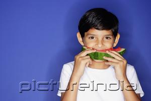 PictureIndia - Boy looking at camera, eating watermelon